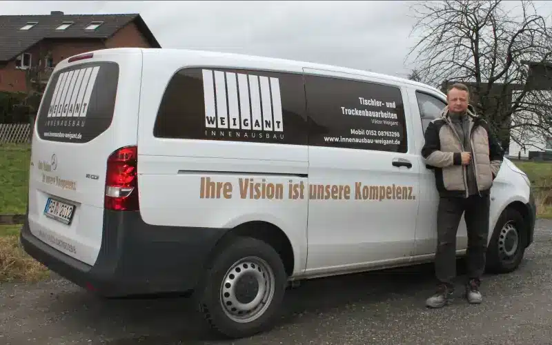 Viktor Weigant neben einem Firmenfahrzeug