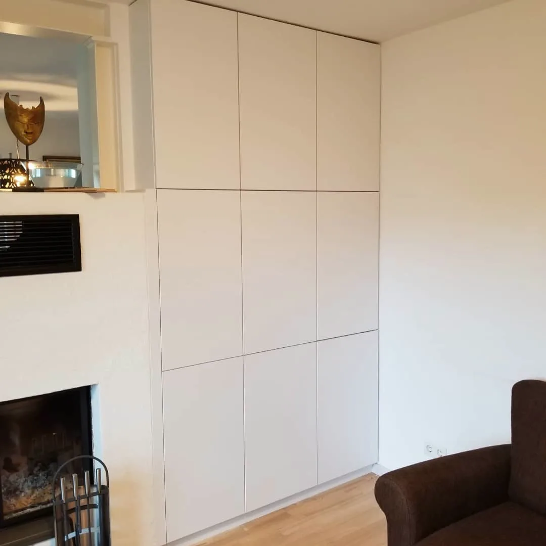 Weißer raumhoher Einbauschrank nach Maß neben einem Kamin