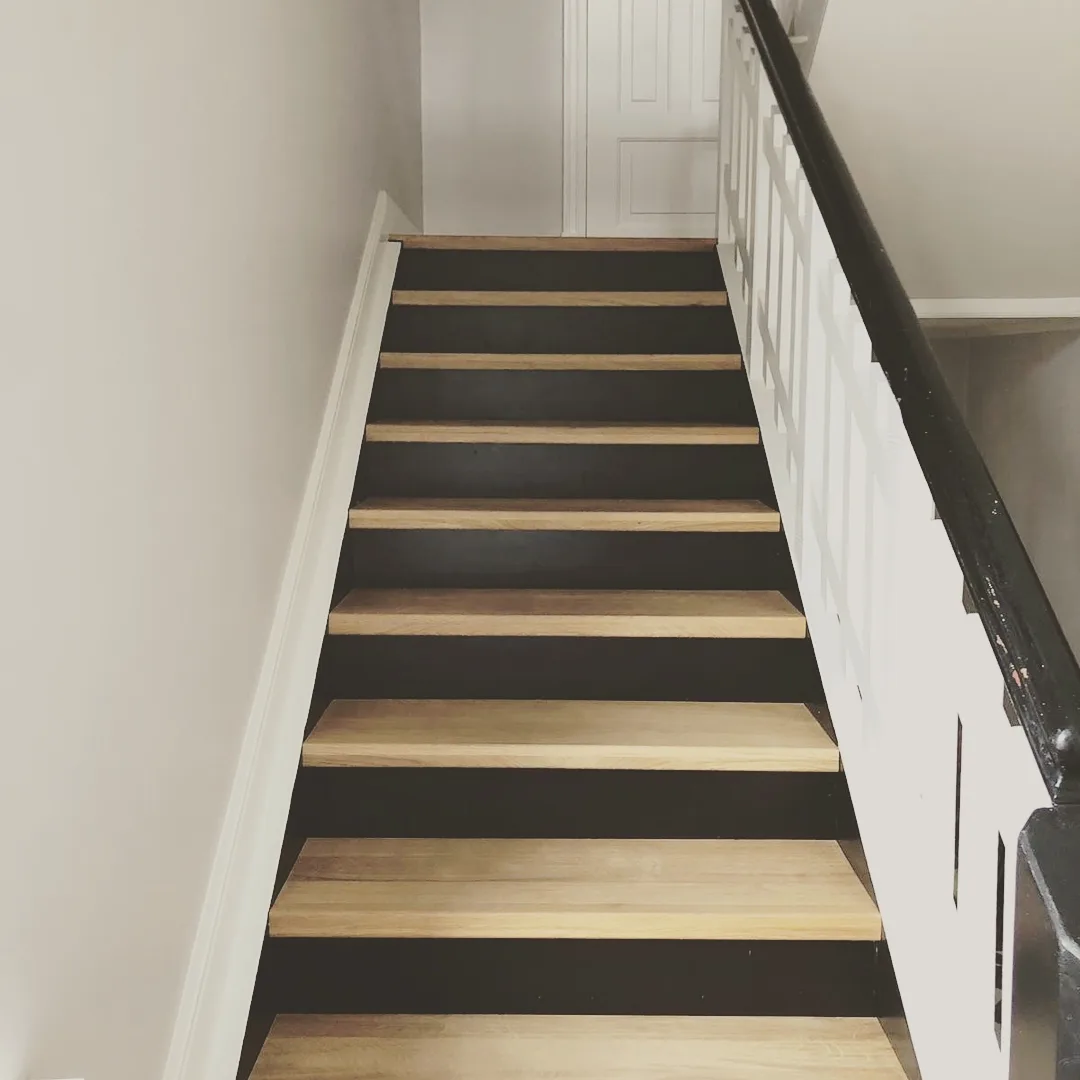 Renovierte Treppe mit Holzstufen und weiß lackierten Setzstufen
