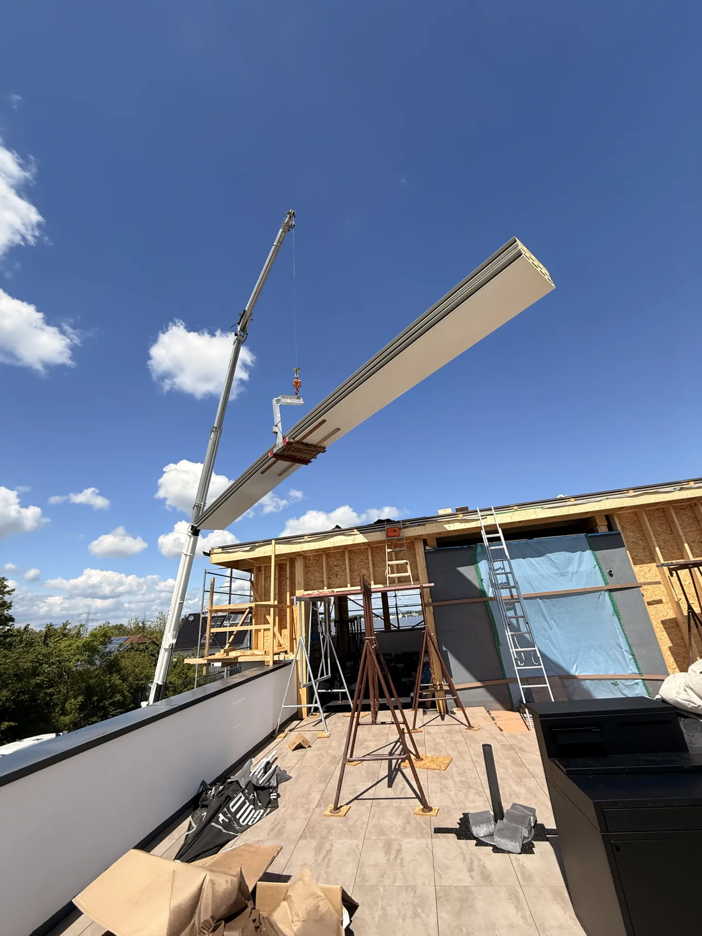 Ein Kran hebt ein Holzbauteil über das Obergeschoss